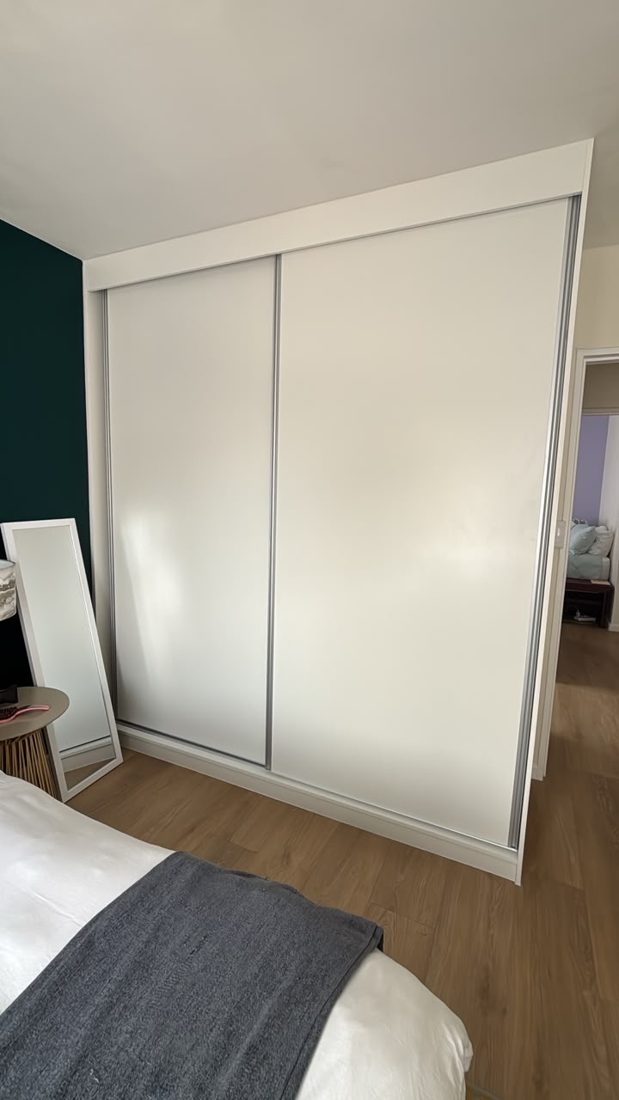 Built-in cupboard with plain white sliding doors before the mirrors were fitted